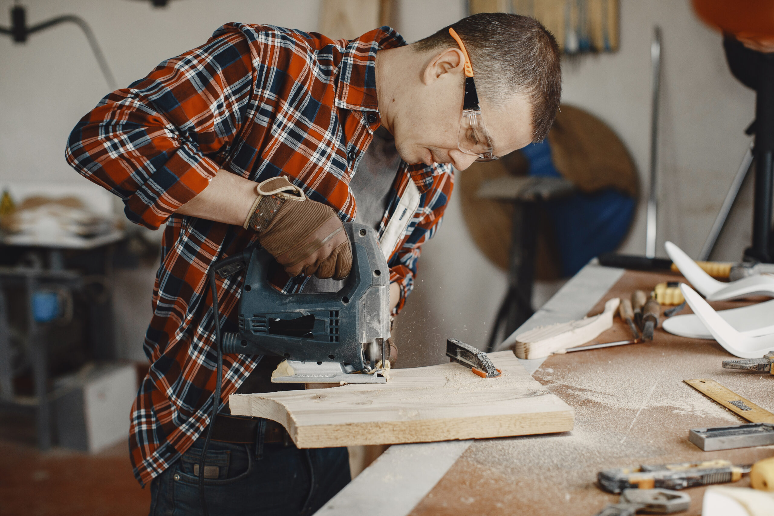 Wood cutting with circular saw. Closeup of mature man sawing lumber.